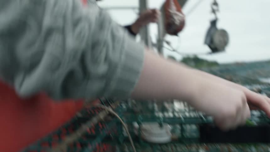 A man ties up the door to a crate on a fishing boat