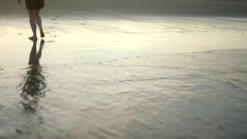 A person walks out of the water on the beach