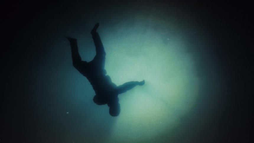 The silhouette of a human body floating and falling through a circle of light