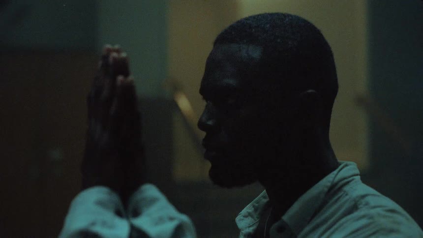 A man walks up to a mirrored surface and places his hand out to it