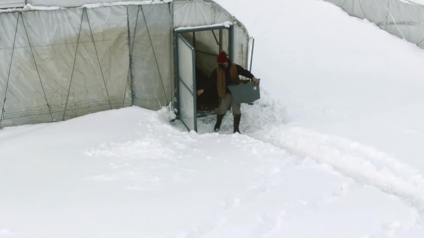 A man walking out of a tent in the middle of the winter