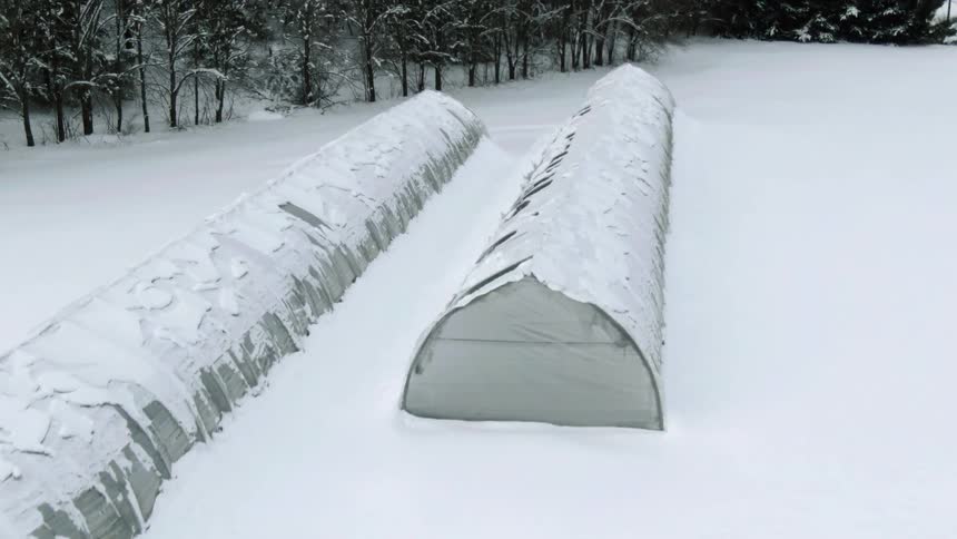 Long snow covered buildings with trees in the distance on a winter day