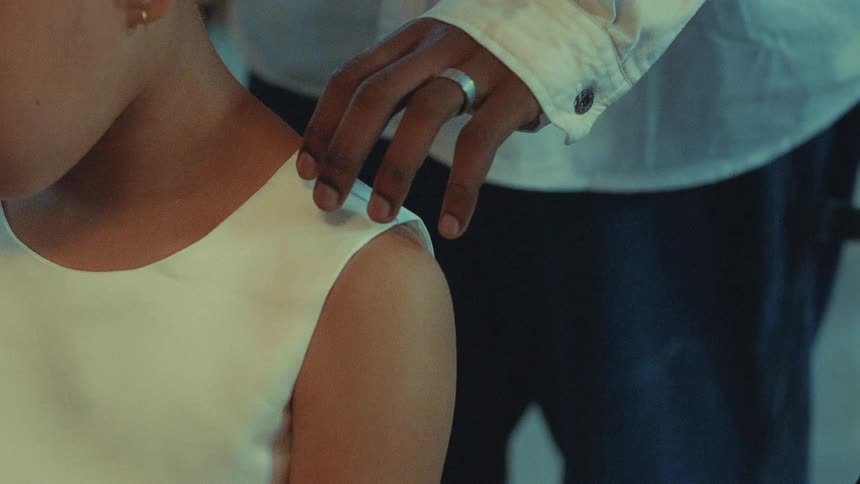 Man with shirt and jeans touches girls shoulder wearing white dress