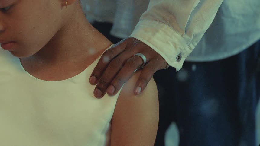 Man with shirt and ring touches girls shoulder with sleeveless dress while snowing
