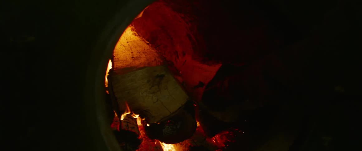Someone is putting chopped wood into the flames in a furnace