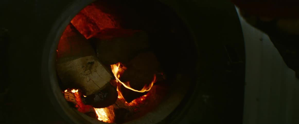 Someone is putting chopped wood into the flames in a furnace
