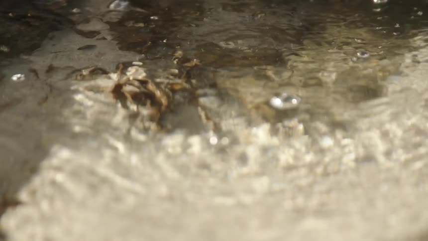 Crystal clear water flows and ripples over sand on a bright day