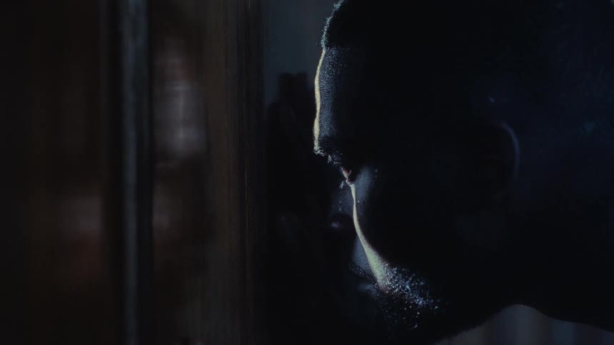 A man puts his hand up against a doorframe and tries to peek through