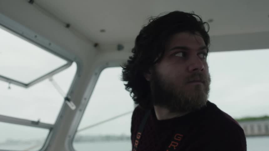 Man stands at helm in boat cabin looking around