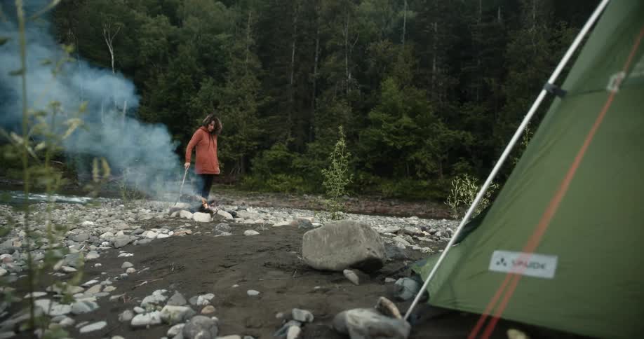 A woman is stirring the campfire