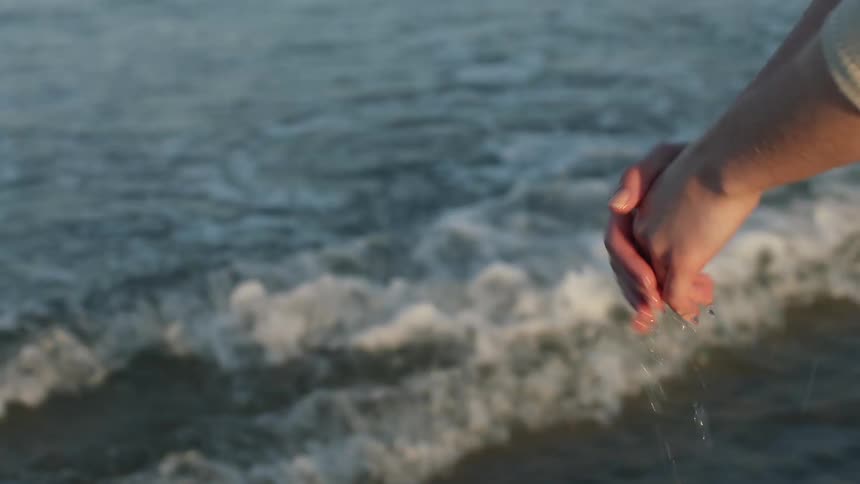 A woman brushes sea water through her hair