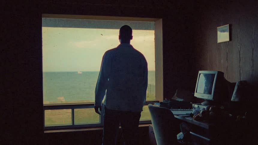 A man walks to look out the window in his house