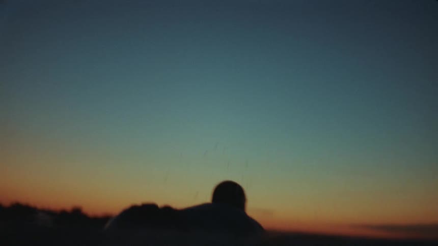 Man swimming alone at the ocean during sunset