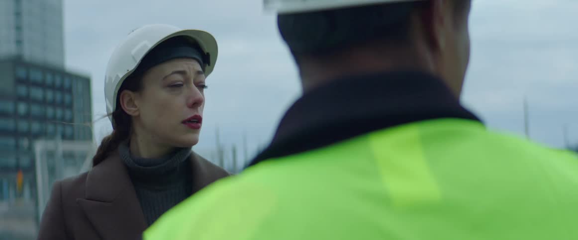 Man and woman wearing safety helmets talking at a construction site