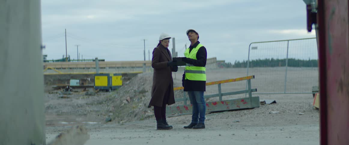 Construction workers discuss plans on a tablet while at a job site