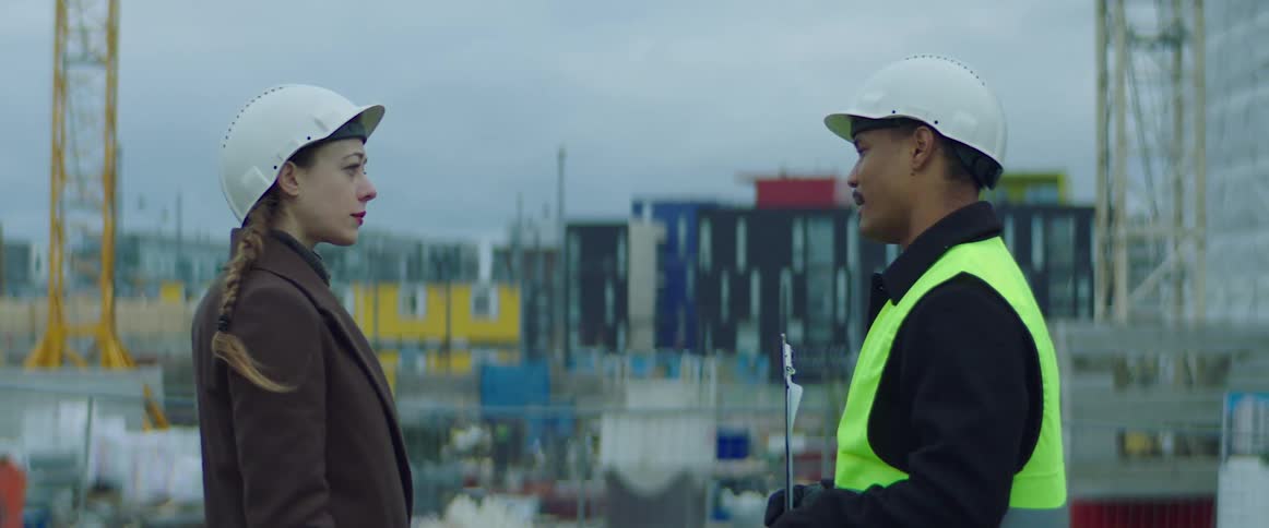 A construction worker talks with another person at a construction site