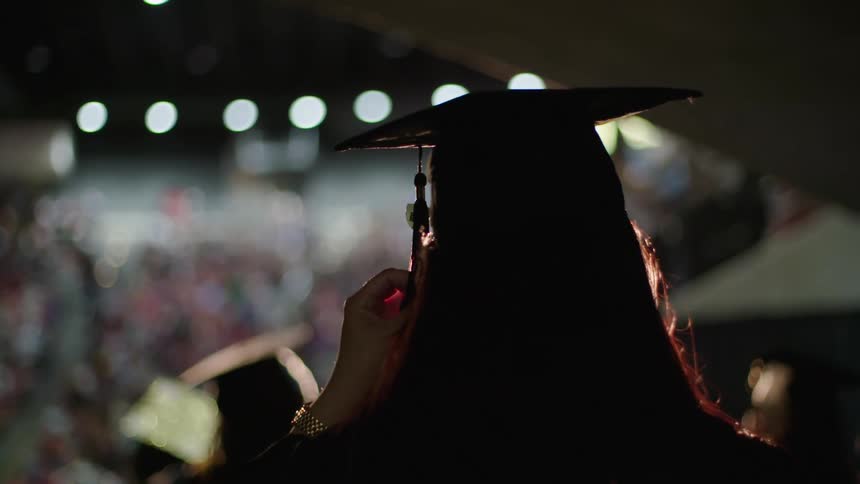 An anxious female graduate touching her tassel on graduation cap
