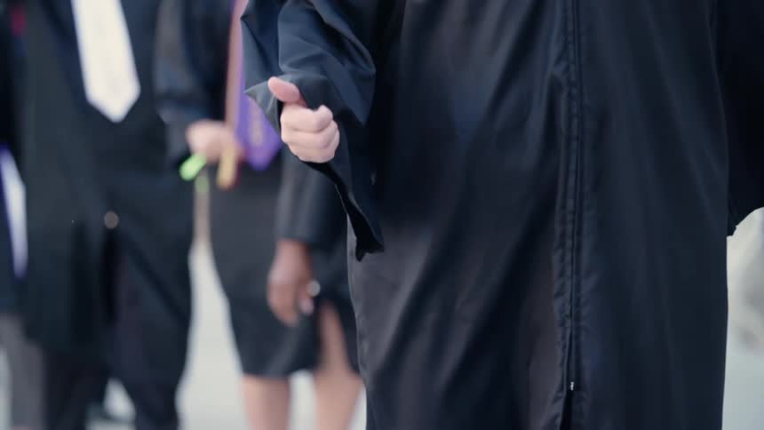 Graduates walk in their black gowns