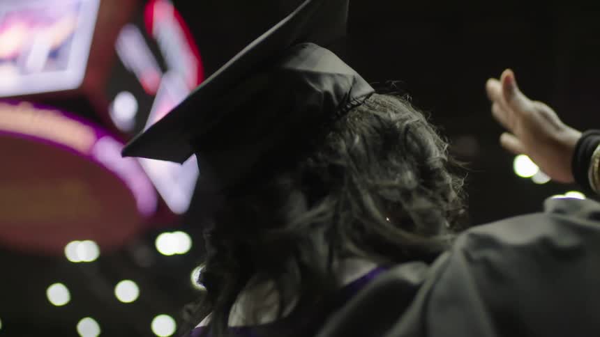 A woman waves and blows kisses as she graduates