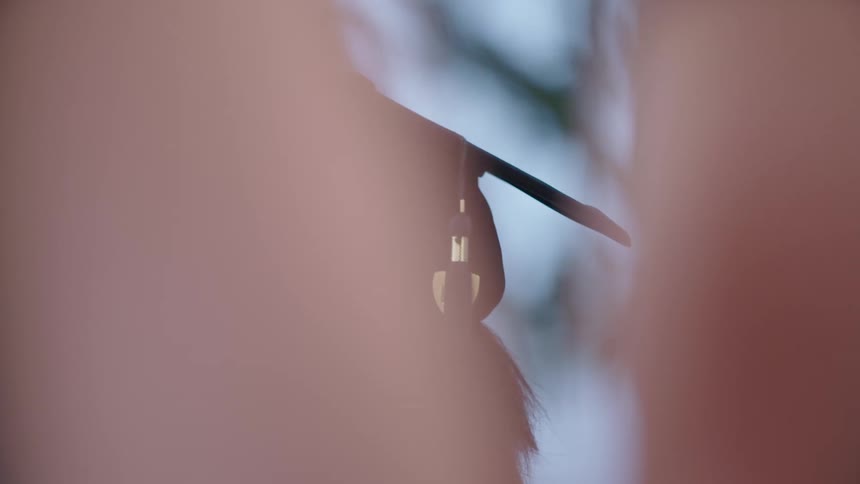 A woman stands outside in her graduation cap and gown