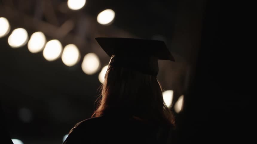 Graduates stand on stage in their caps and gowns
