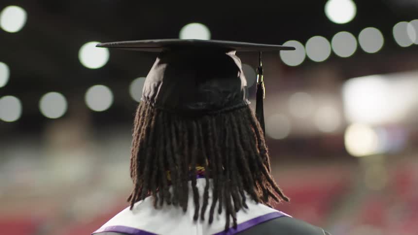 A black woman walks across the stage at her graduation