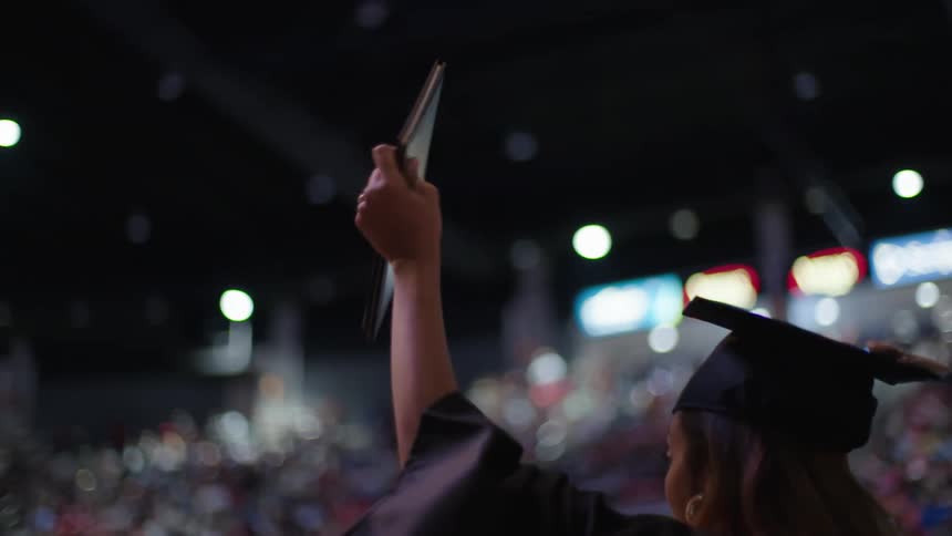 A graduate waves at the crowd
