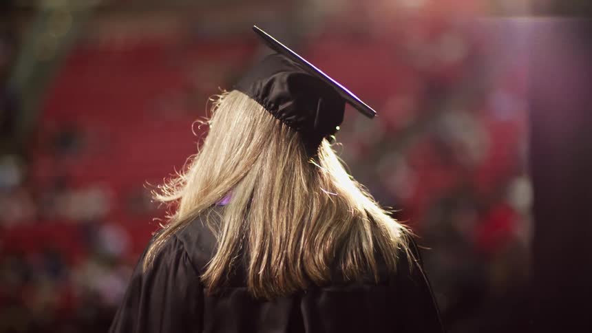 Blonde female wearing a black graduation cap walking out
