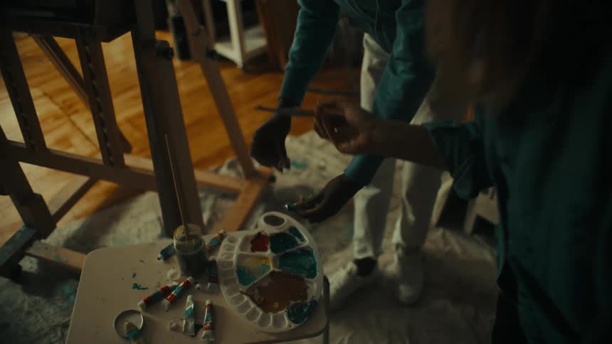A group of painters work on a piece inside a studio