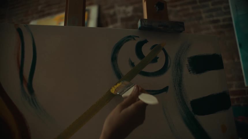 A teenager paints an abstract painting next to another girl