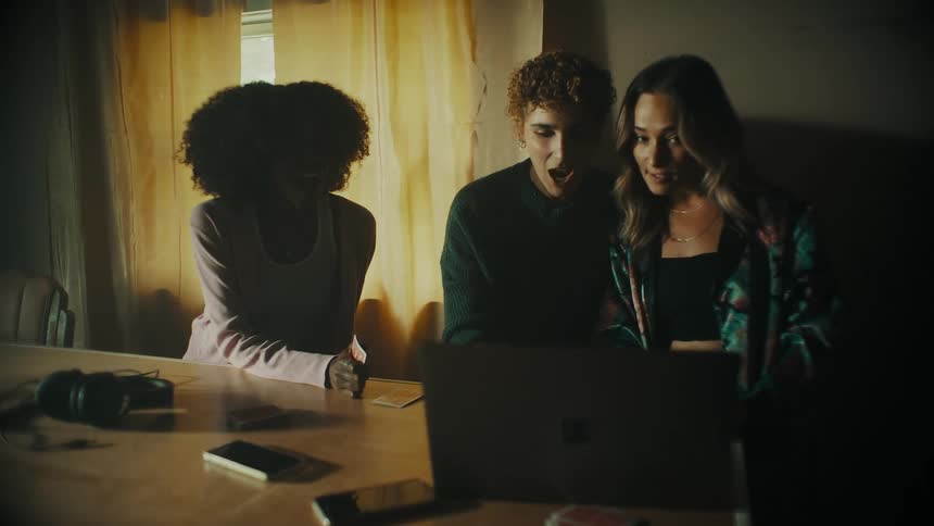 A woman brings a laptop over to show other women something on it