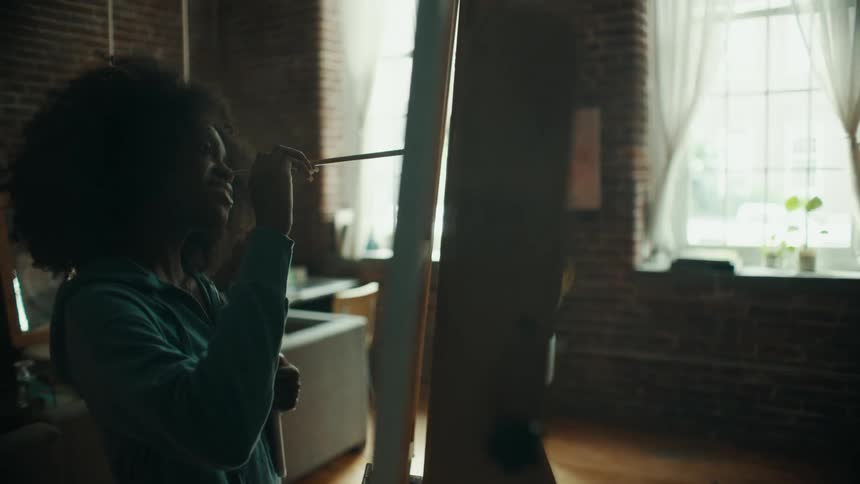 Young black girl painting a blank canvas alone in a room inside the house