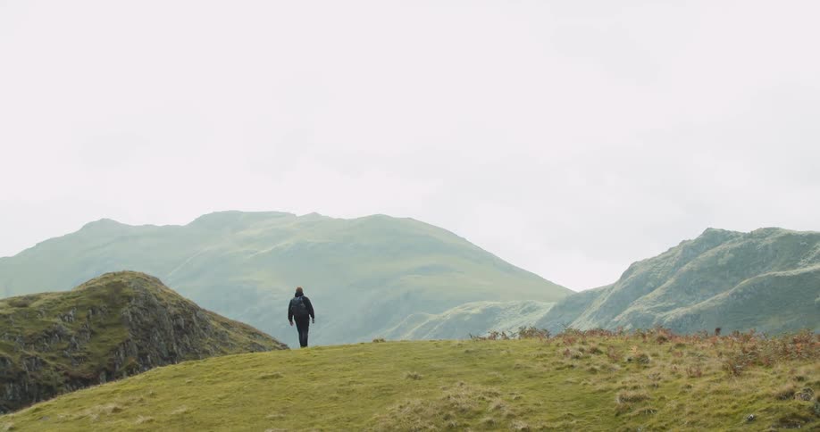 A man hiking a top the hills stops to look outward