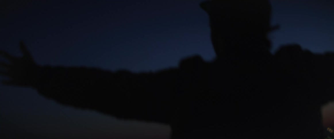 A man spins happily with his arms outstretched overlooking the city