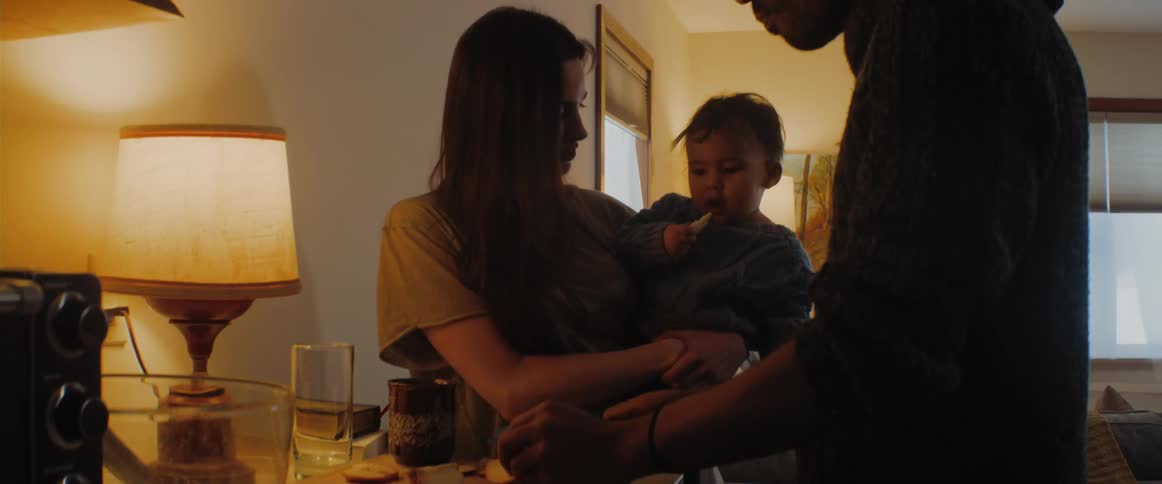 Father slices fruit as he and mother feed their child