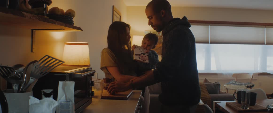A man cuts fruit in the kitchen for his wife and son
