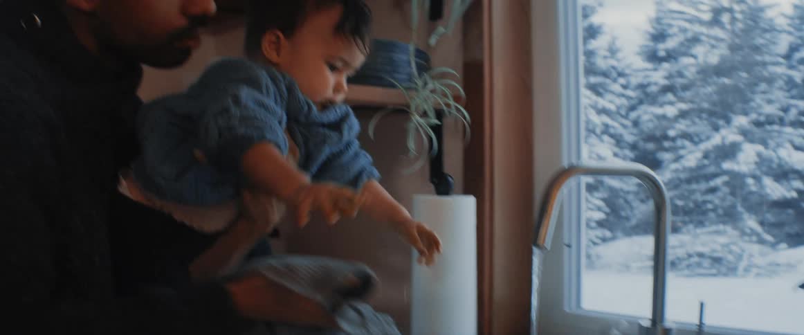 A man washes a babies hands in the sink