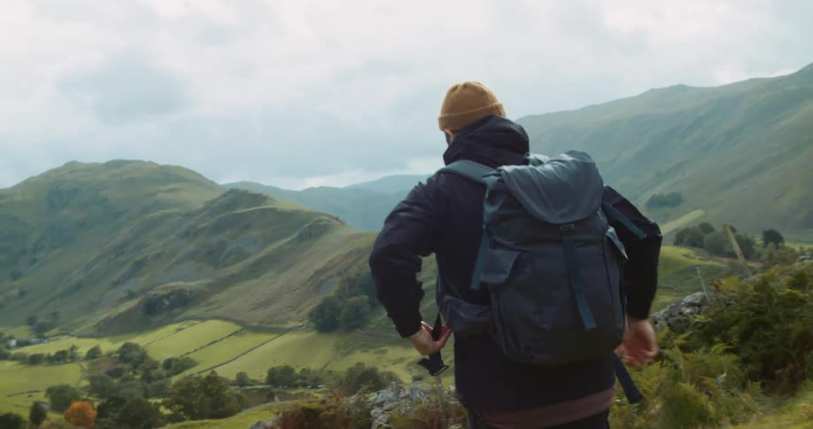 A man straps his backpack on his back and continues on his hike