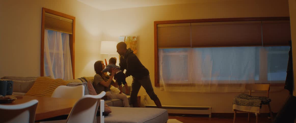 A man swings his son in the air as the boys mom watches on