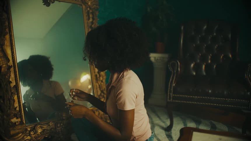 A woman puts on make up in front of a large mirror