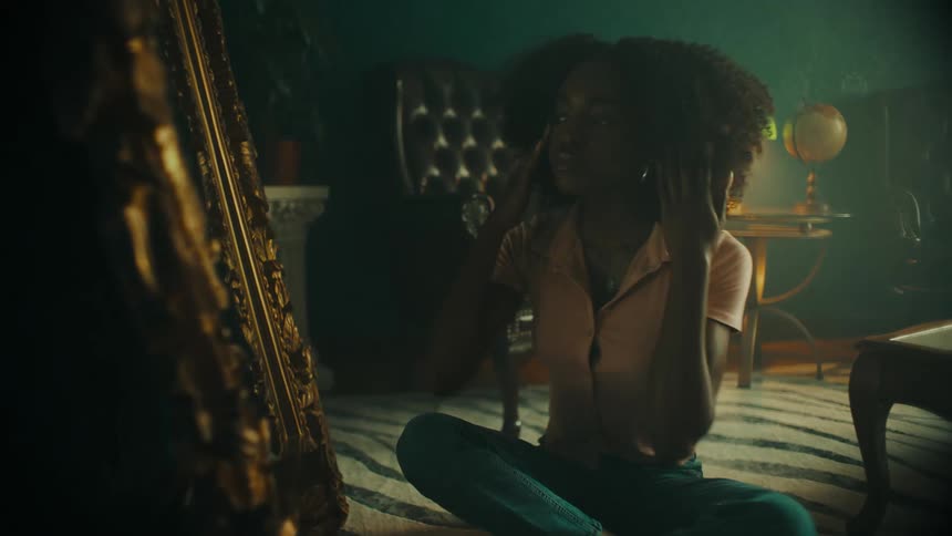 A woman sits in front of the mirror and brushes her hair