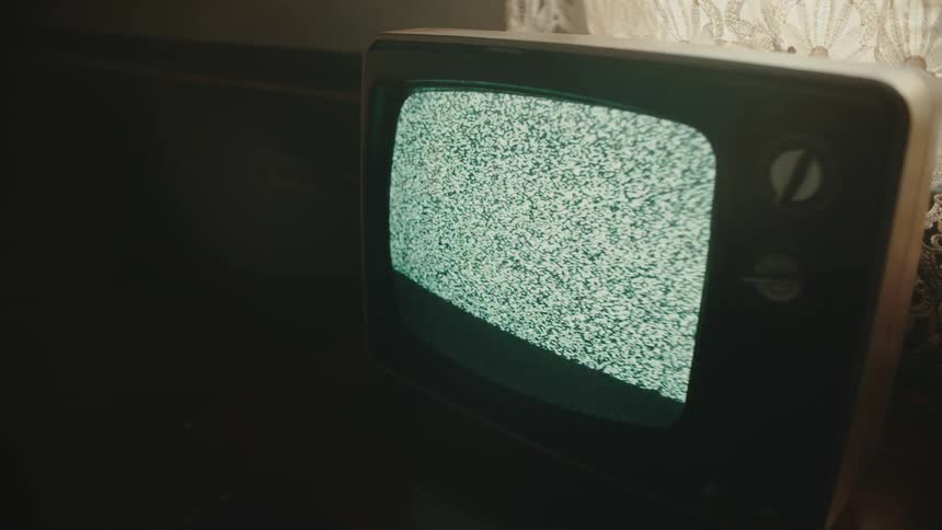 Old television sitting near window has a screen showing a snowy signal