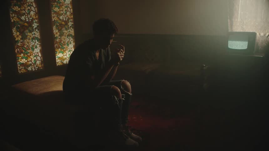 A person cracks their knuckles while sitting in a room with a television playing static