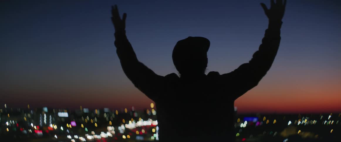 A man happily outstretches his arms as his overlooks the city skyline