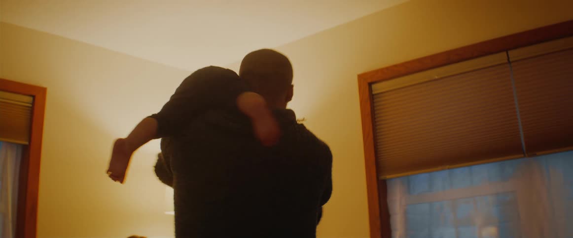 A father spins his son happily on his shoulder