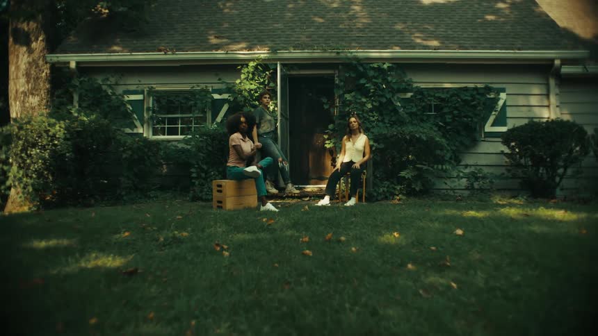 Three women posing in front of a house sitting and standing with attitude and focus