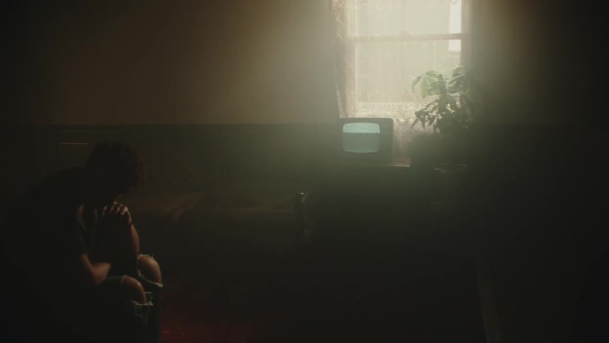Woman sits in smoky room with television