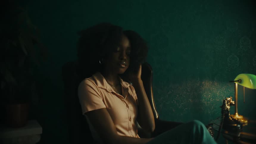 A woman circles in her home and sits down in a chair