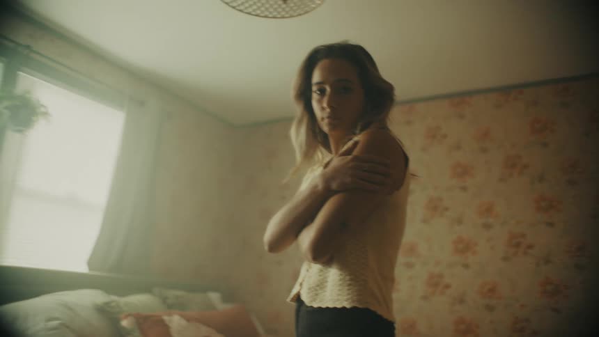 A woman walks around her bedroom