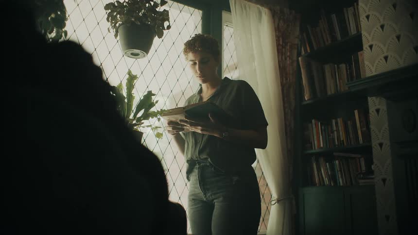 A woman reads a book by the window
